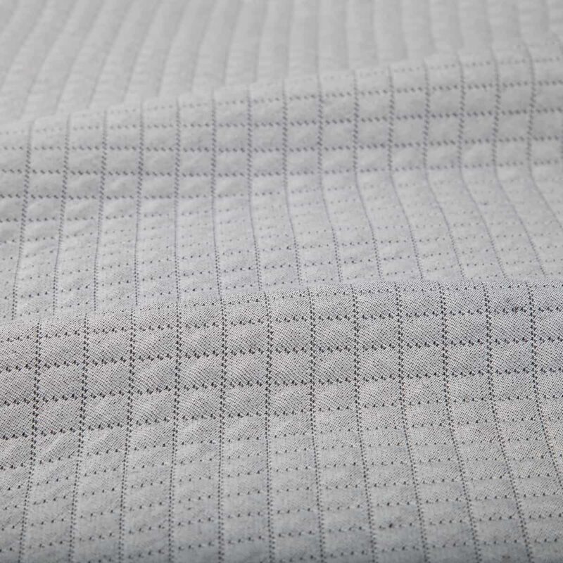 detailfoto van een grijze bedsprei in ruitjes