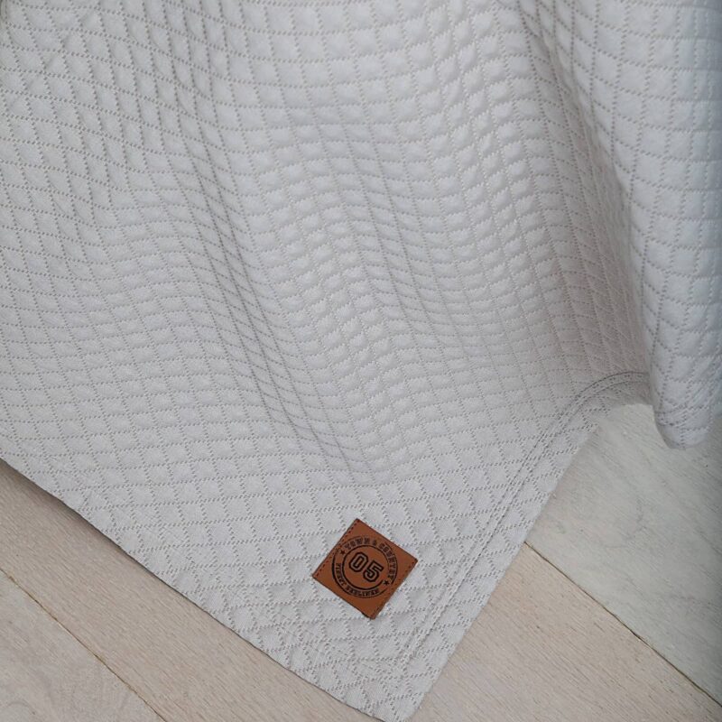 houten vloer met zandkleurige luxe bedsprei