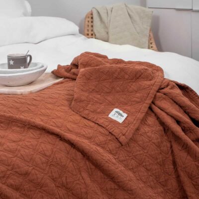 bed met terracotta gekleurde sprei