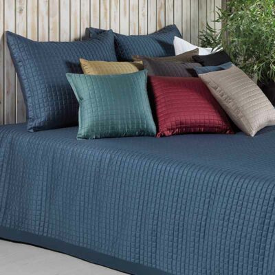 bed met gekleurde satijnen kussens en blauwe bedsprei