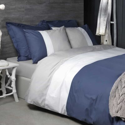 bed met grijze plaid en dekbedovertrek in blauw, wit en grijs van katoen percal