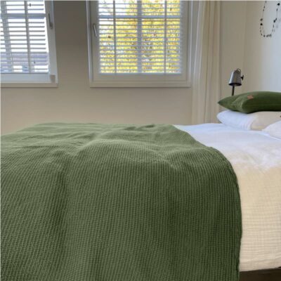 bed in slaapkamer met groene wafel sprei