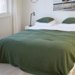 bed in slaapkamer met wit dekbed en groene wafel sprei