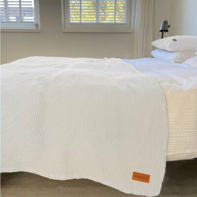 slaapkamer met een bed en lichte muren, wit wafelkatoenen sprei op het bed