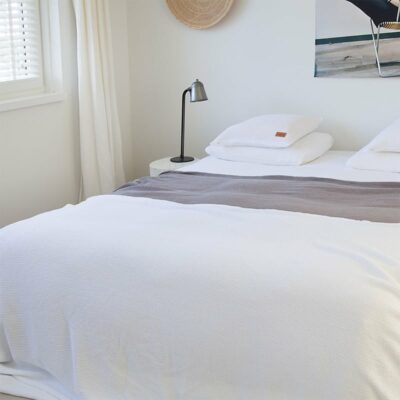 slaapkamer met een bed en lichte muren, wit wafel sprei op het bed