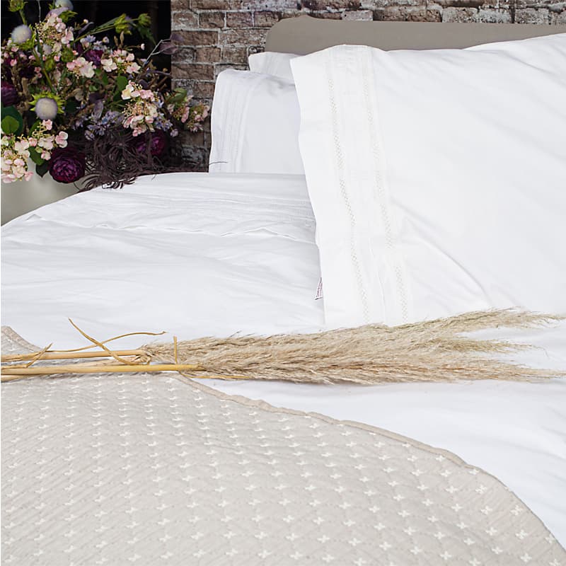 strobladeren op bed met beige sprei en wit dekbedovertrek