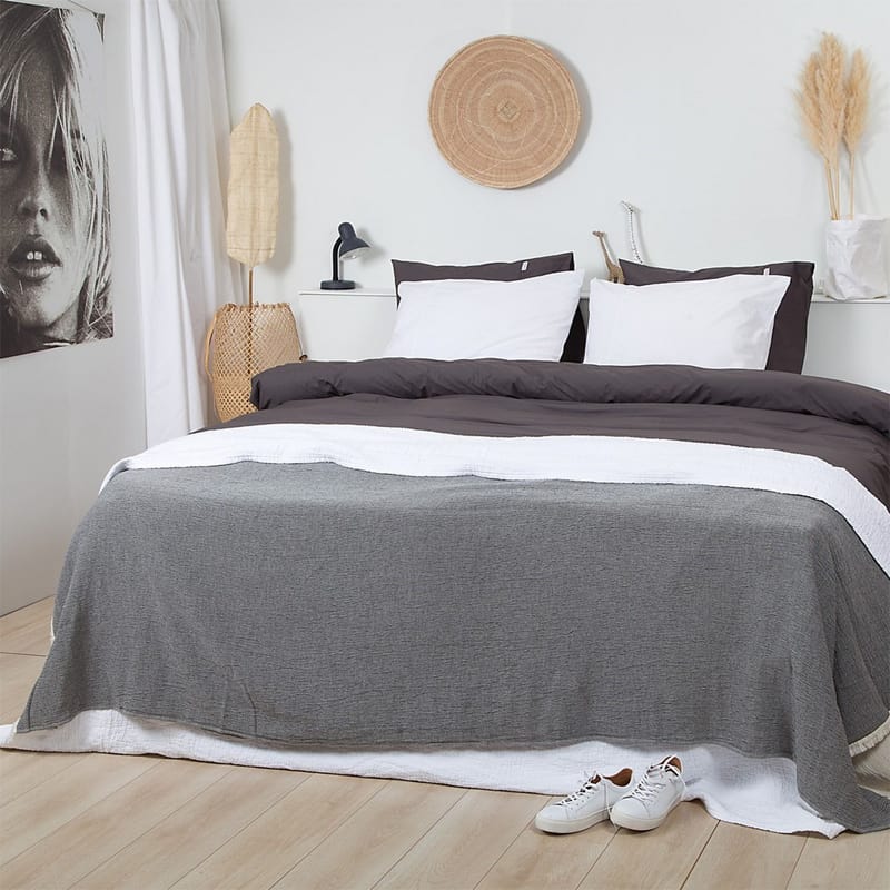slaapkamer met bed, houten vloer. grijze bedsprei en wit met grijs percal katoen dekbedovertrek