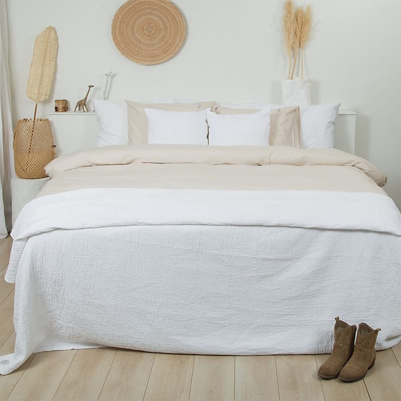 slaapkamer met houten vloer en wit bed met wit-zand dekbedovertrek