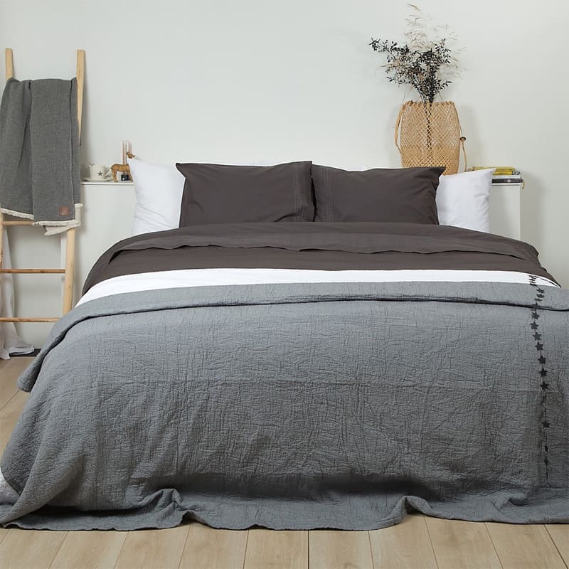 slaapkamer met houten vloer, grijze bedsprei en grijs dekbedovertrek broderie
