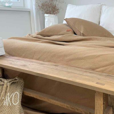 bedsprei in goud tint met houten voetbankje