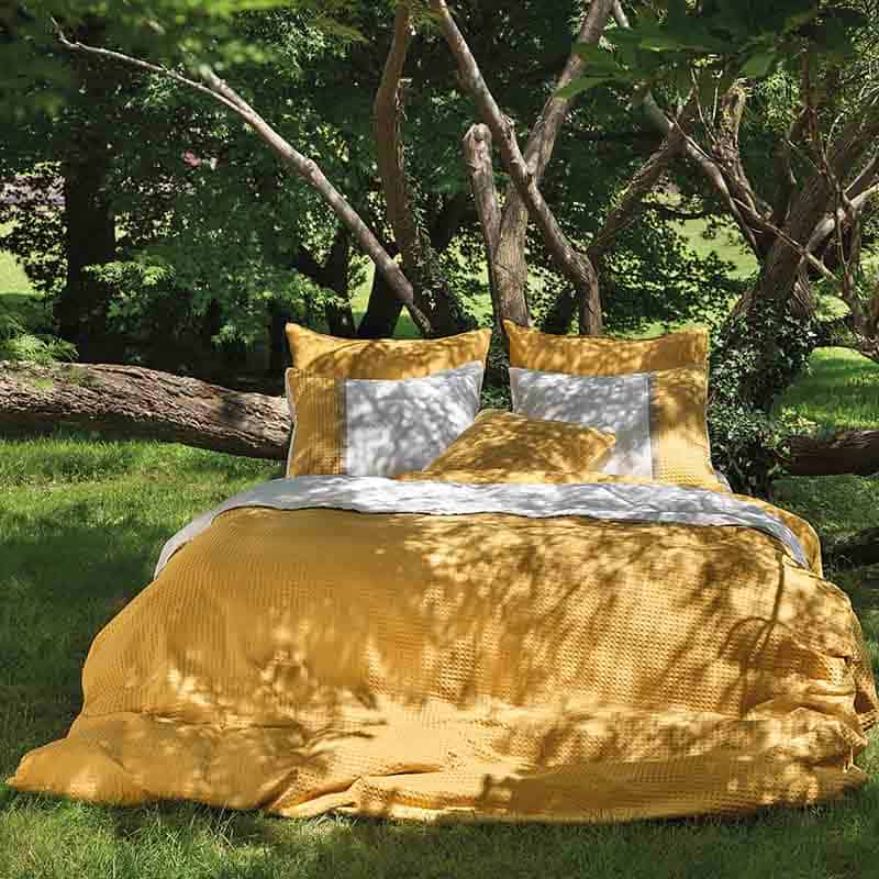 bed in tuin met geel wafel dekbedovertrek