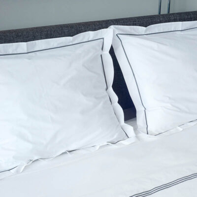 bed met 2 kussens en witte bovenlakens van katoen