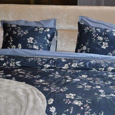 bed met blauw gebloemd bovenlaken en kussens