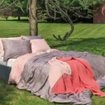 bed op gras met luxe lakens en bedspreien opgemaakt