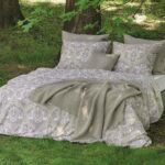 bed op gras met sprei, kussens en lakens met print