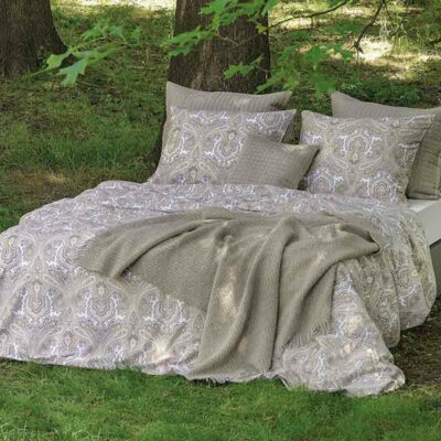bed op gras met sprei, kussens en lakens met print