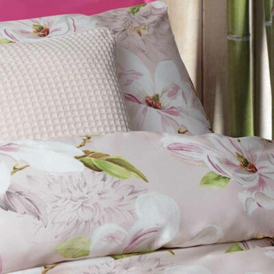 opgemaakt bed met roze satijnen lakens in bloemen dessin