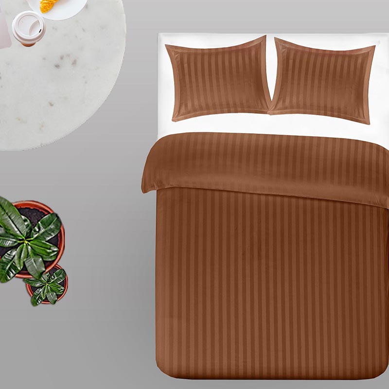 plant, wit tafeltje en bed met terracotta dekbedovertrek in strepen dessin