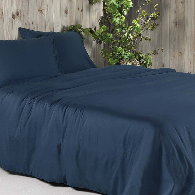 slaapkamer met bed en donkerblauw dekbedovertrek