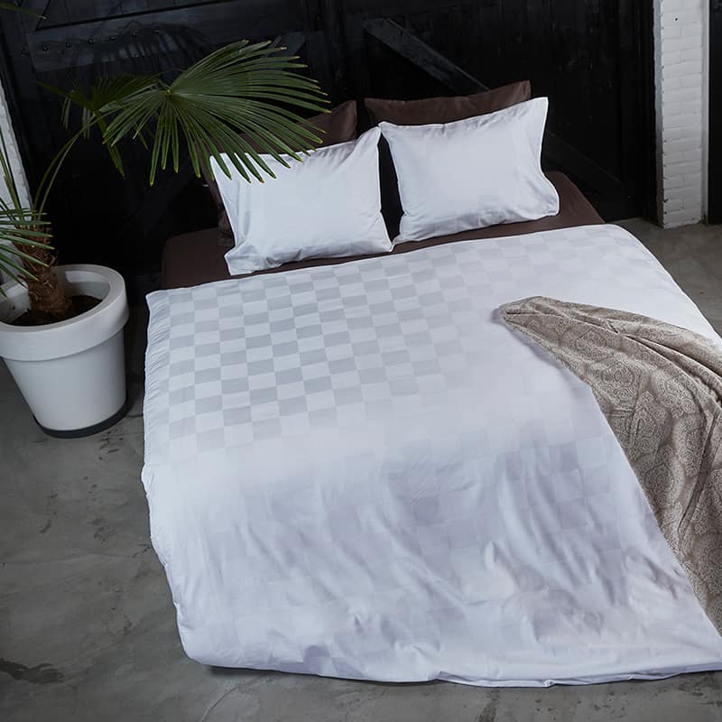 slaapkamer met plant, plaid en wit dekbedovertrek in luxe uitstraling