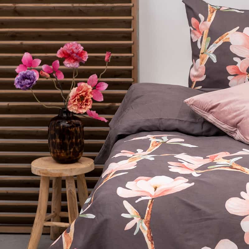 vaas met bloemen en een paars/ grijs dekbedovertrek met bloemen