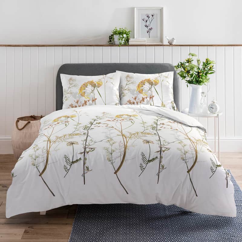 slaapkamer met witte muur, bed met zomer dekbedovertrek in planten motief
