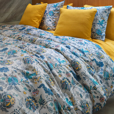 bed met gele kussens en gebloemd blauw-grijs dekbedovertrek