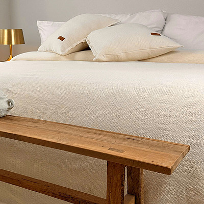 houten voetbank en katoenen bedsprei in ecru