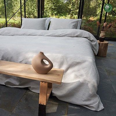 houten bankje en bed luxe opgemaakt met linnen dekbedovertrek