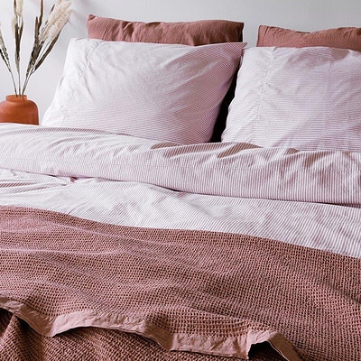bed met roze dekbedovertrek en katoenen bedsprei
