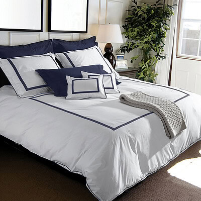 slaapkamer met luxe wit dekbedovertrek met blauwe bies